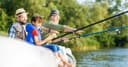 A grandfather, a father and a boy fishing together from a jetty in summer