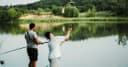 Two anglers on a wooden pontoon at a lake, one of them casting